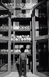 10 Feb 2004, Cambodia --- A child looks at the piles of skulls, victims of the Khmer Rouge regime, displayed at a memorial to the victims at the Choeung Ek killing fields. --- Image by © Andrew Holbrooke/Corbis